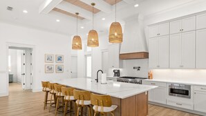 Una cucina moderna con un'isola grande, mobili bianchi e pavimento in legno.