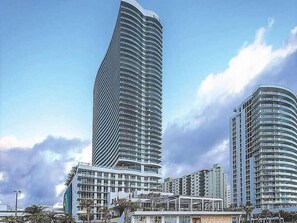 A modern high-rise building with a curved facade, surrounded by other high-rise buildings.