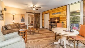Un salon confortable avec un canapé, une table basse, un téléviseur et un coin repas comprenant une table et des chaises.