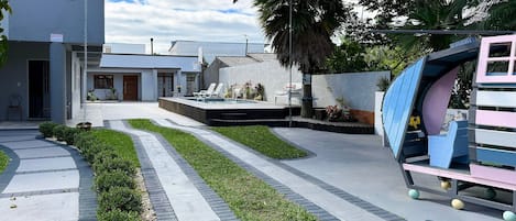 A modern residential area with a swimming pool, a covered outdoor seating area, and a well-maintained garden.