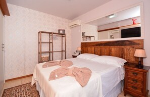 A bedroom with a wooden headboard, a large mirror, a bedside table with a lamp, and a wardrobe. - Ampla Casa com Piscina Ponta do Papagaio (Palhoça)