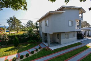 Una casa de dos pisos con balcón, entrada para coches y un jardín bien cuidado.