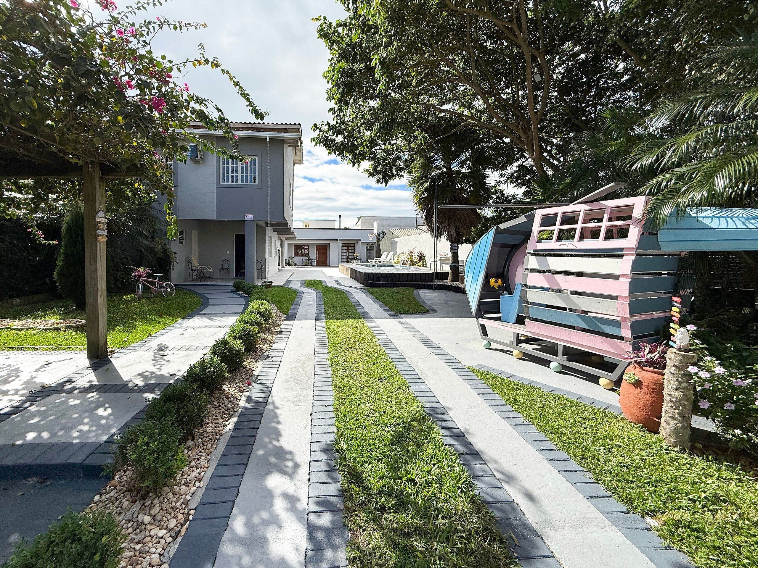 A pathway leading to a building with a covered outdoor seating area and a colorful play structure.