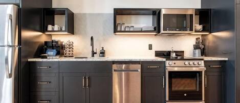 Una cocina moderna con electrodomésticos de acero inoxidable, muebles oscuros y suelo de madera.