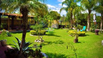 Un jardín cuidado con diversas plantas, un banco y una estatua.