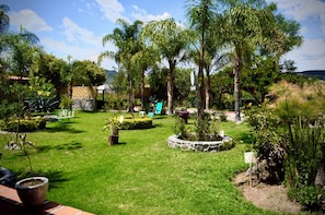 A well-maintained garden with various plants and trees, a paved pathway, and a stone wall. - Hotel Paraje Atlixco (Atlixco)