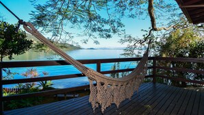 A hammock on a wooden deck overlooking a body of water with a clear sky. - Casa à Beira Mar no Ribeirão -SDI012 (Florianópolis)