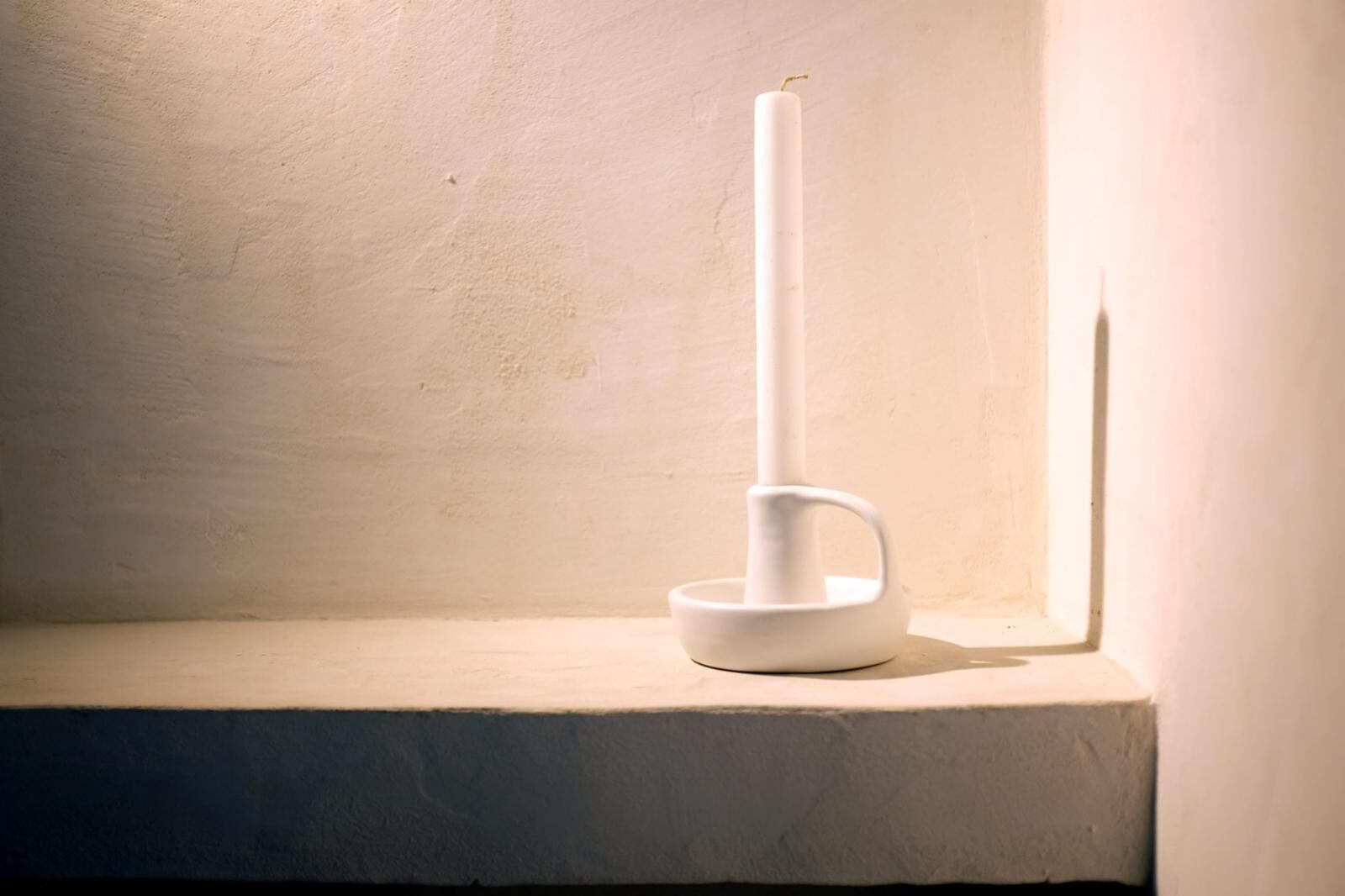 Un chandelier blanc est posé sur une étagère dans une pièce aux murs unis.