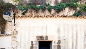 A stone building with a small entrance and a staircase leading inside. - Il Corvo di Pietra   Nido Blu (SCICLI)