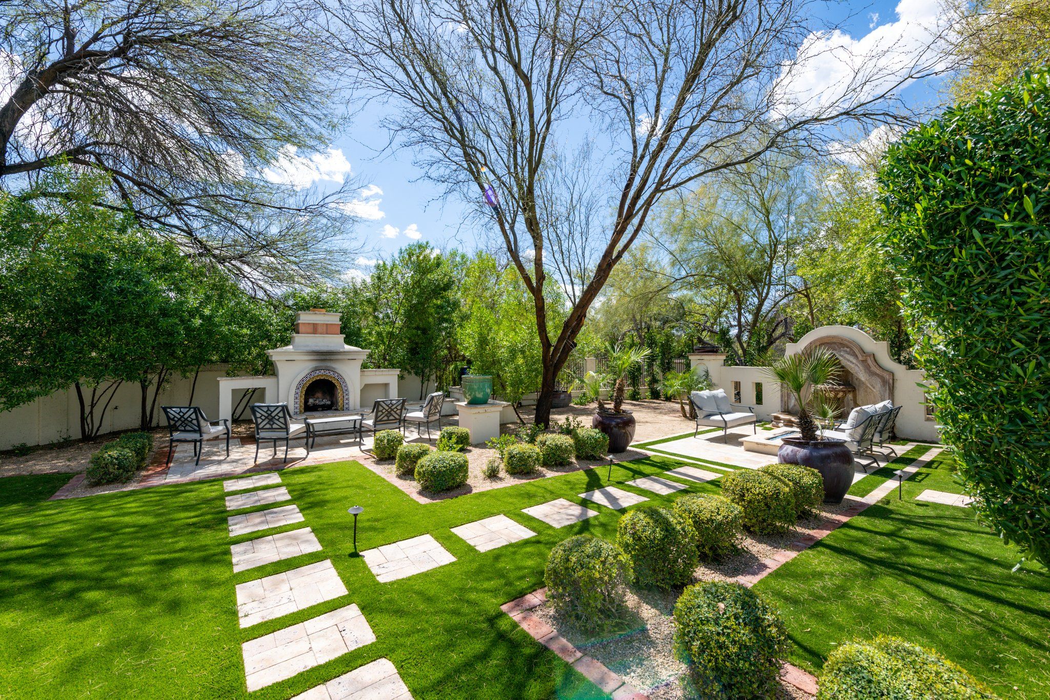 Um jardim bem cuidado com um espaço de pátio, móveis de exterior e uma lareira decorativa.