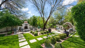 A well-maintained garden with a patio area, outdoor furniture, and a decorative fire pit.