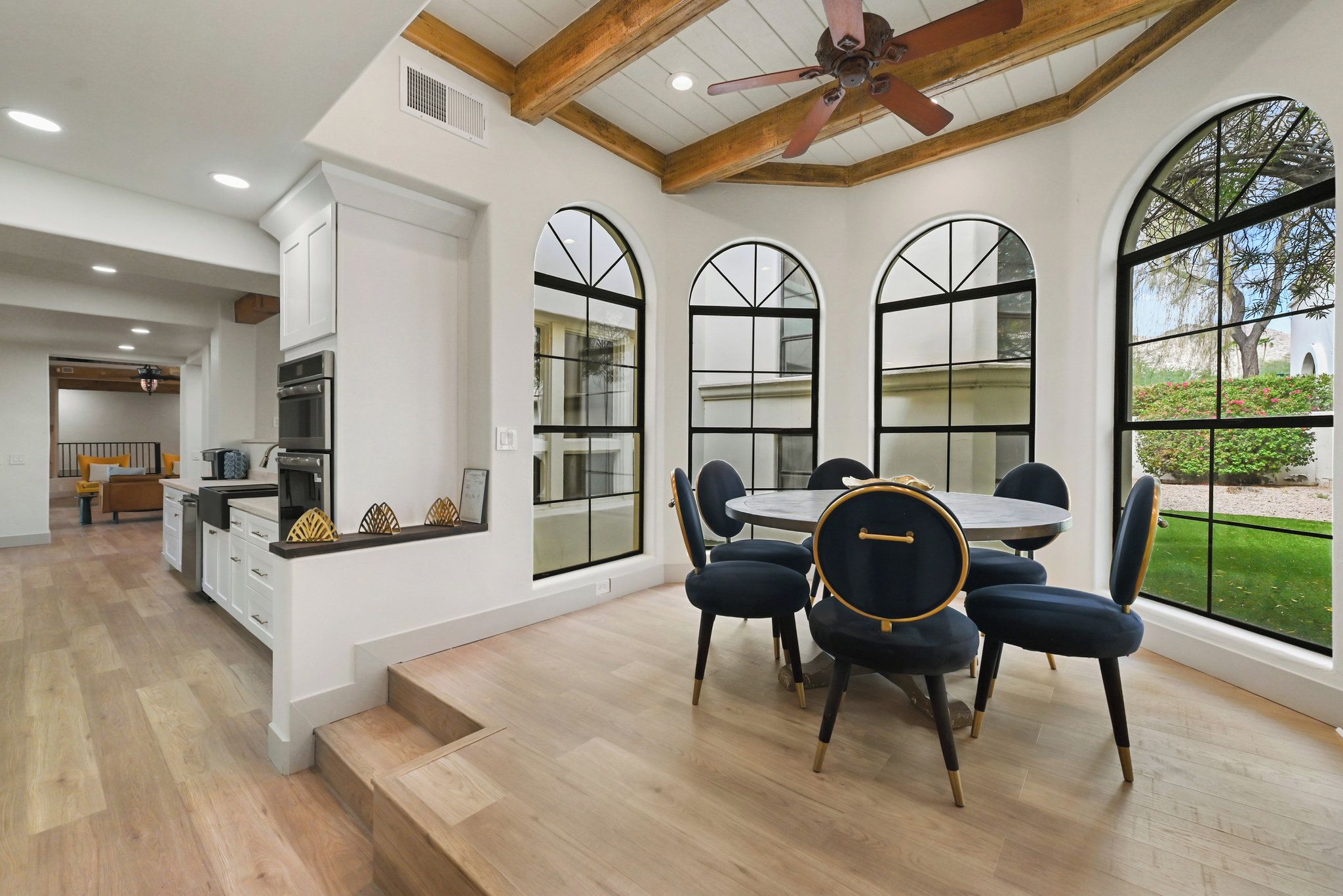 A spacious kitchen with modern appliances, a dining area with a round table and chairs, and large windows offering views of the outdoors.