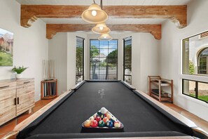 A pool table with billiard balls in a room with wooden beams, a potted plant, and a window with blinds. - Valley Vista Estate: 12BR Paradise Valley, Swim-Up Bar, Putting Green, Sleeps 30 (Paradise Valley)