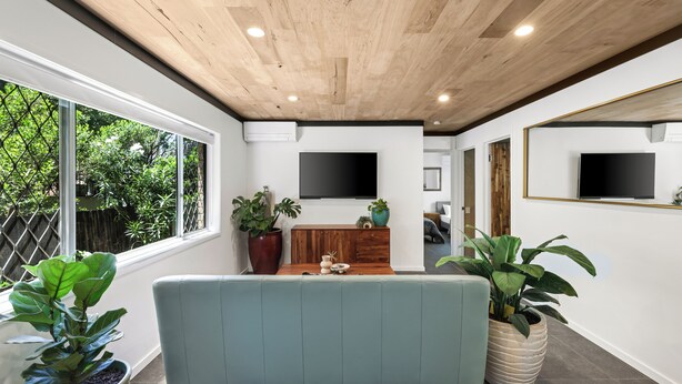 Un salon moderne avec un plafond en bois, de grandes fenêtres et des plantes en pot.
