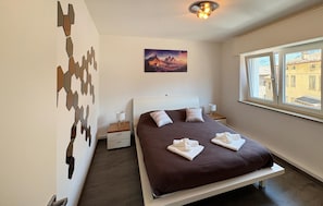 A bedroom with a bed, a painting, a window, and a wall decoration. - Nice home in Longarone with WiFi (Longarone)