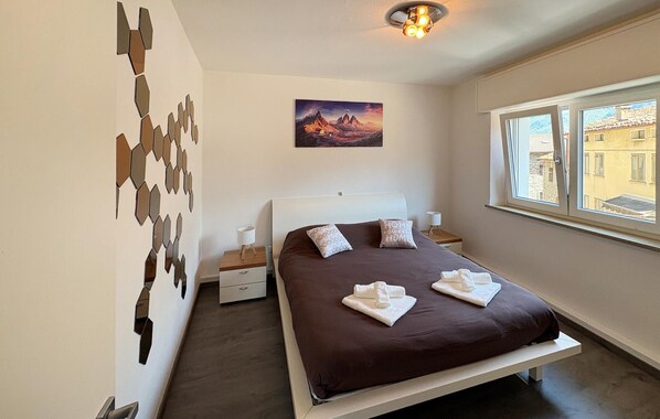 Ein Schlafzimmer mit Bett, einem Bild, einem Fenster und einer Wanddekoration.