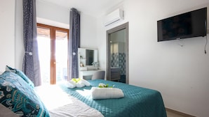 A hotel room with a bed, a TV, a bathroom, and a view of the outside.