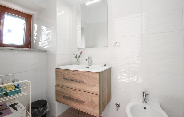 Een badkamer met een witte wastafel, een houten kastje en een spiegel erboven.
