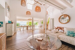 A spacious living area with a glass coffee table, wooden flooring, and a view of the outdoors. - Charming family villa Désir des Îles (Sainte-Anne)