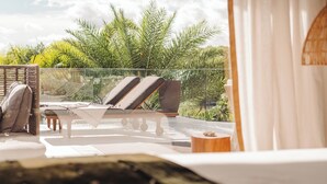 Un balcon équipé de deux chaises longues, d’une petite table et d’une chaise.