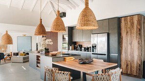 Une cuisine moderne dotée d’un îlot central, de luminaires suspendus et d’un meuble en bois.