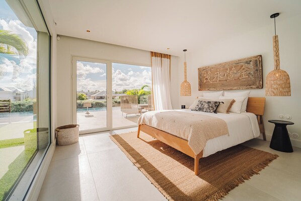 Een moderne slaapkamer met een groot bed, uitzicht op de natuur en een rustieke decoratie aan de muur.