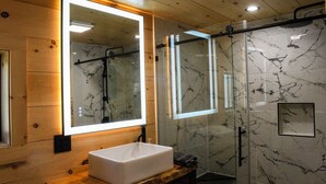 Een moderne badkamer met een houten wastafelmeubel, een grote spiegel en een douchecabine met glazen wanden.