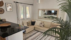 Ett modernt vardagsrum med ett svart matbord, en beige soffa och en randig matta.