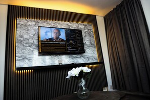 Ein Fernseher an einer Marmorwand, darunter eine Blumenvase.