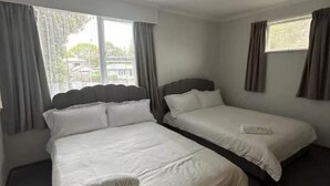 Quarto de hotel com duas camas de solteiro, cada uma com almofada rotulada 'AWA'.