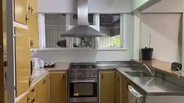 Uma cozinha compacta com armários amarelos, um fogão de aço inoxidável e uma pia.