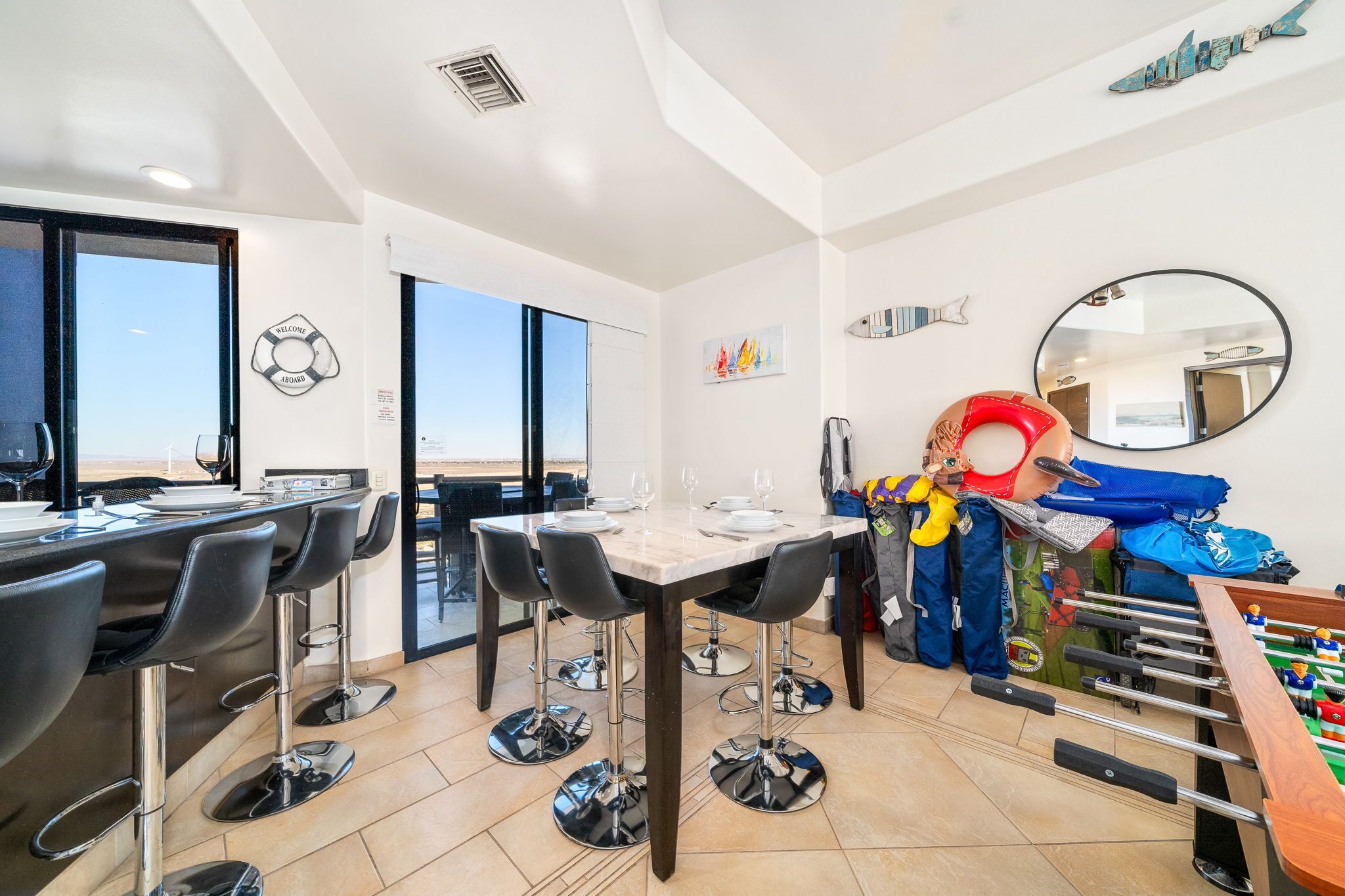 A dining area with a bar, high chairs, and a foosball table.