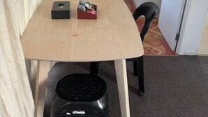A small, compact room with a wooden table, a black stool, and a white cabinet with a microwave. - 4 Beds Including 1 Sofa Bed in 1 Bedroom+1 Lounge (Auckland)