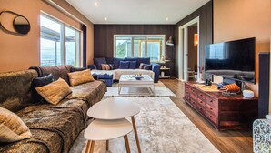 A modern living room with a sofa, coffee table, TV, and a wooden cabinet. - Stunning home in Bokn with WiFi (Bokn)