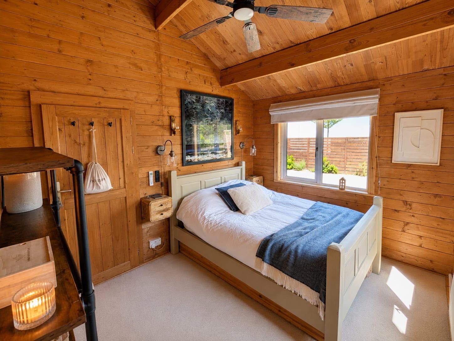 A wooden cabin bedroom with a bed, a window, and a ceiling fan.