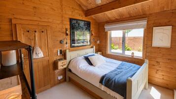 A wooden cabin bedroom with a bed, a window, and a ceiling fan.