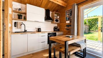 A modern kitchen with white cabinets, a wooden countertop, and a dining table with benches.