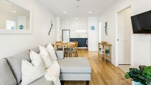 Una sala de estar moderna con un sofá gris, una mesa de comedor y una cocina al fondo.