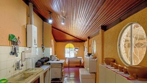 A kitchen with wooden ceiling beams, a sink, a stove, and a window with a view.