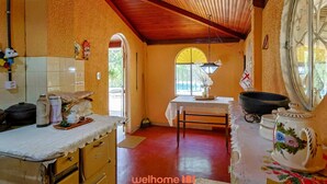 A kitchen with a wooden ceiling, a table with a vase, and a window with a view.