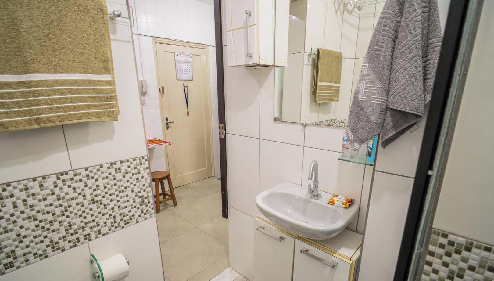 A bathroom with a sink, mirror, and towel rack. There is a door leading to another room.