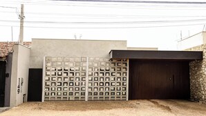 A modern building with a metal gate, a stone wall, and a large wooden door.