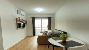 Un espacio habitable compacto con kitchenette, comedor y zona de estar con sofá y mesa de centro.