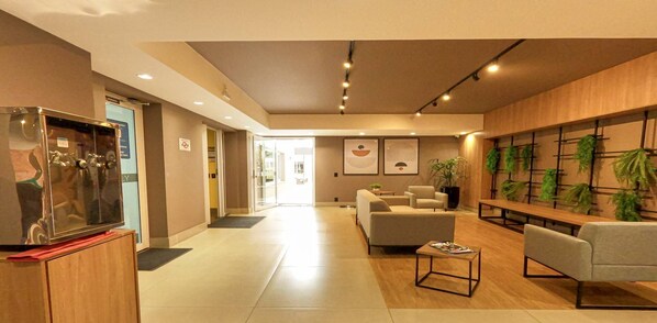 En moderne hotellobby med receptionsdisk, siddeområde og en vægmonteret plantebesætning.