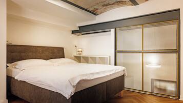 A modern bedroom with a large bed, a wooden floor, and a sliding glass door with a metal frame.