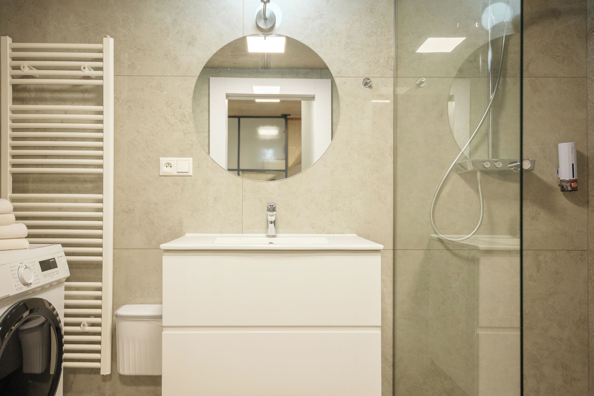 Ein modernes Badezimmer mit Waschmaschine, Waschbecken und einer Duschkabine.