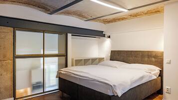 A bedroom with a bed, a sliding glass door, and a ceiling with exposed beams.