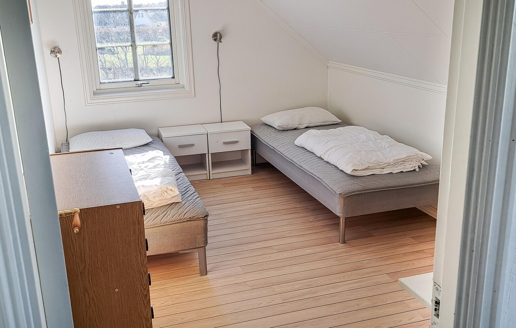 Ein Schlafzimmer mit Bett, Nachttischen und einem Fenster.