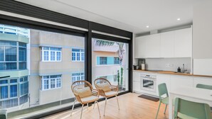 Een moderne keuken met witte kasten, een houten aanrecht en een eethoek met twee stoelen en een tafel.