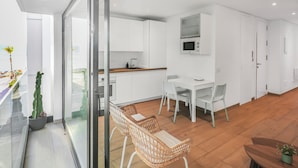 Een moderne keuken met witte kastjes, een magnetron, en een eethoek met witte stoelen en een tafel.